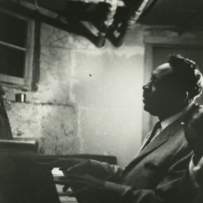 portrait of Otis Spann playing piano in a dingy room