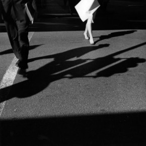 lower halves of man and woman walking across street and casting their shadows