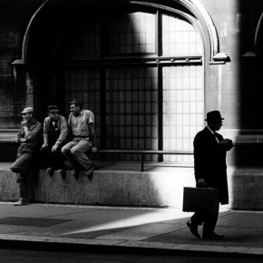 business man walking down street past three men in worker uniforms