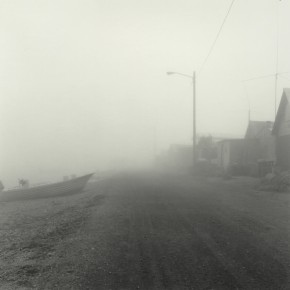 view of foggy street lined with houses, street light and a boat
