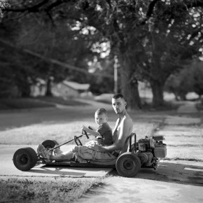 Thomas Putnam with Thomas Putnam Jr. on his lap driving a stripped down motorized vehicle