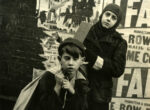 Thumbnail image: Boys in front of a poster-clad brick wall, New York City