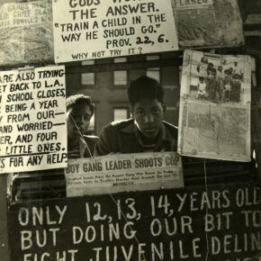 A photograph of two young boys looking through a window of posters.